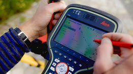 Nahaufnahme eines Leica-Vermessungsgeräts, auf dem ein Punkt zur Grenzfeststellung in Dresden digital mit einem Stift auf dem Display ausgewählt wird