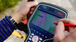 Nahaufnahme eines Leica-Vermessungsgeräts, auf dem ein Punkt zur Grenzfeststellung in Dresden digital mit einem Stift auf dem Display ausgewählt wird